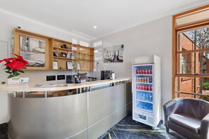 A reception desk with a glass partition, a vending machine, and a seating area. - Comfort Inn Coach & Bushmans (Seymour)