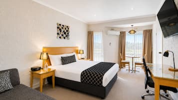 A hotel room with a bed, bedside tables, a desk, a chair, a TV, and a window with curtains.