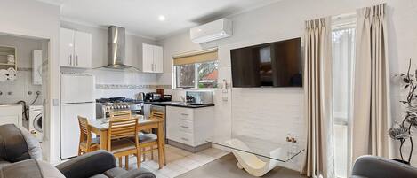 Una cocina moderna con comedor, televisor y una mesa de centro de vidrio.