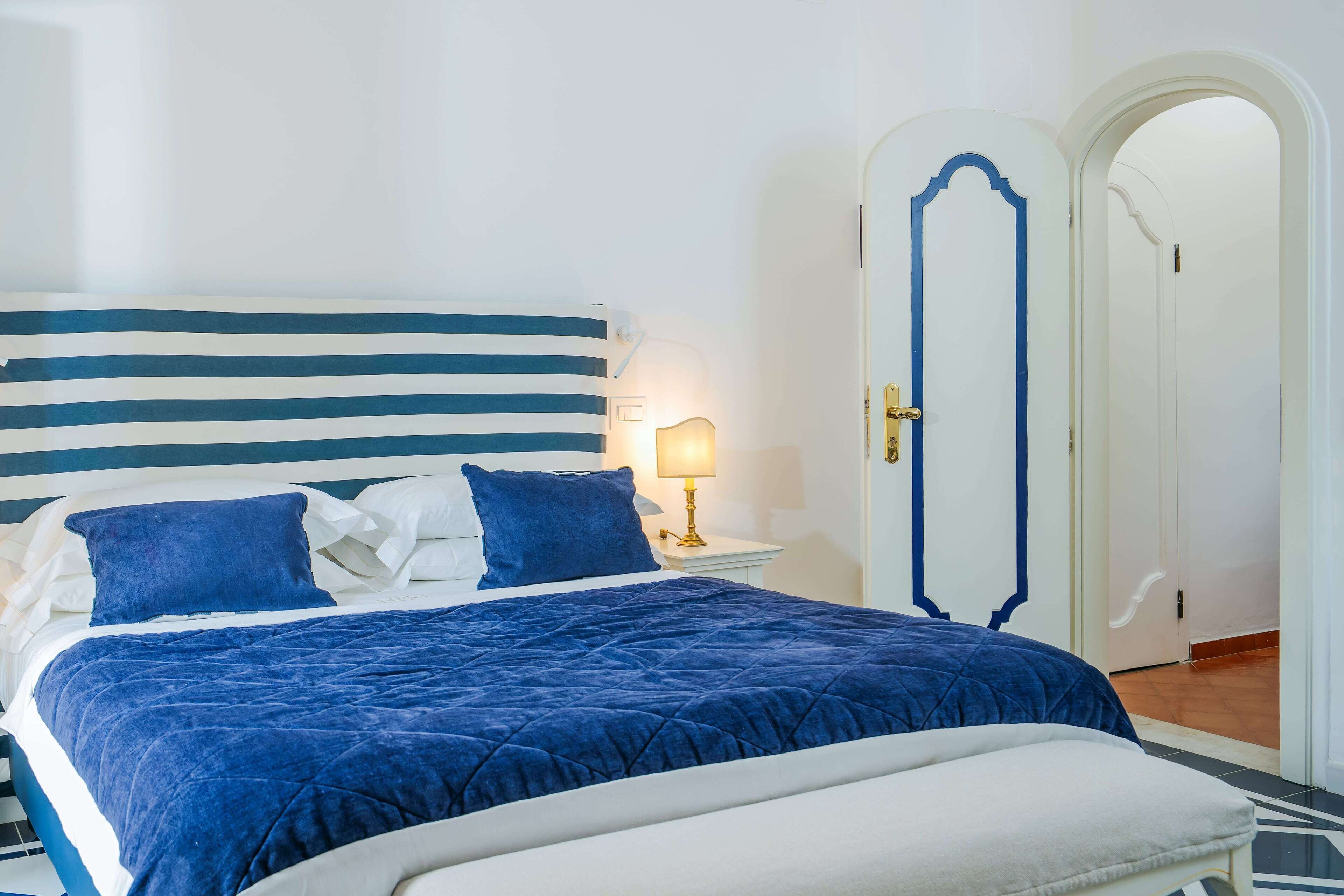 A bed with a striped headboard, a blue quilted bedspread, and two pillows.