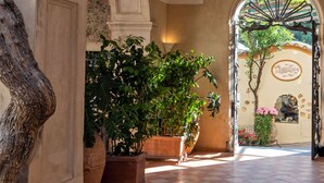 Un pasillo abovedado con un gran tronco de árbol, plantas en macetas y un candelabro.