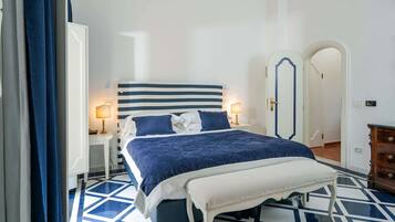 Ein Schlafzimmer mit einem großen Bett, Nachttischen mit Lampen, einer Bank und einem Kleiderschrank.