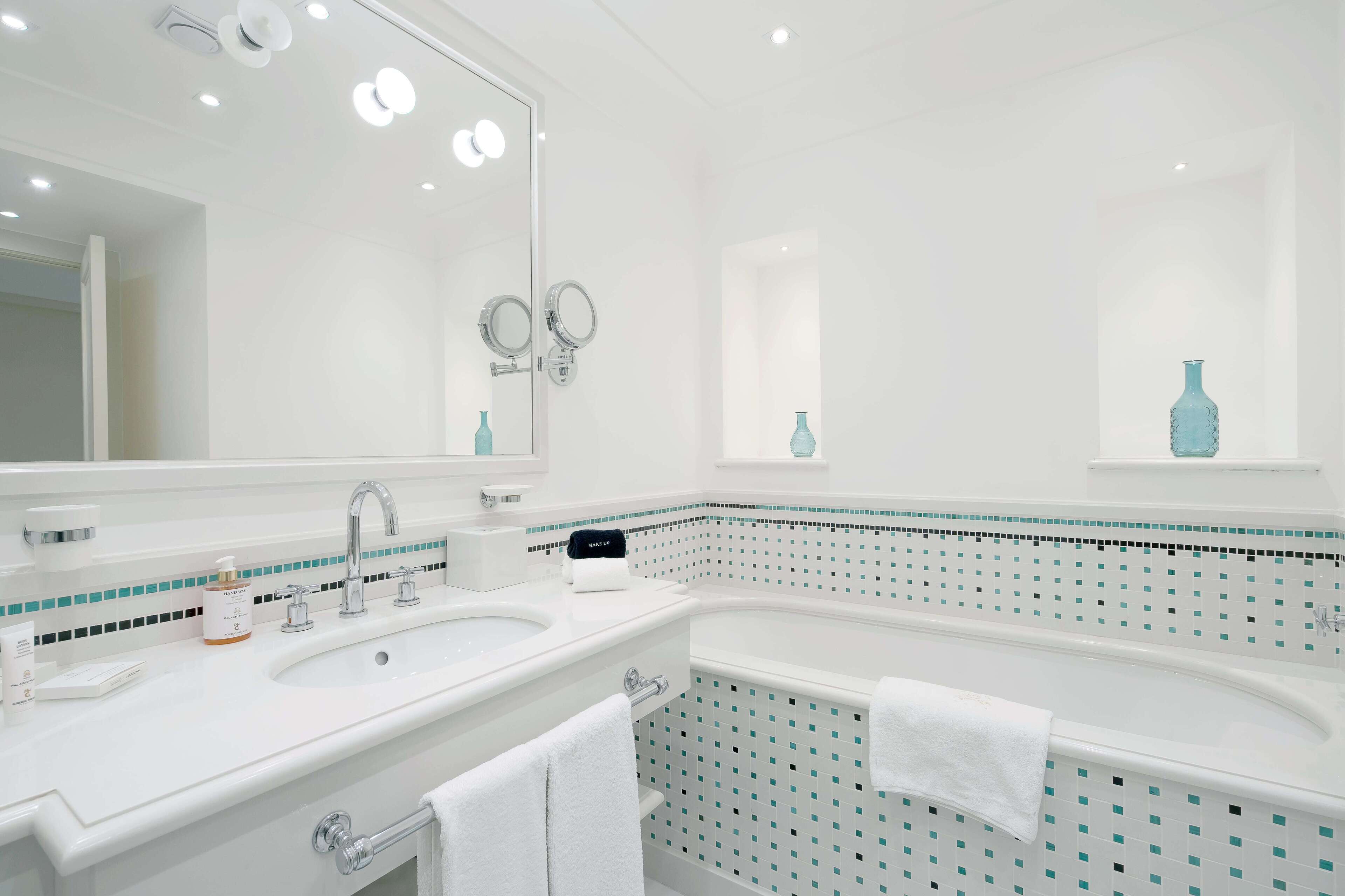 Une salle de bain moderne avec un lavabo blanc, un grand miroir et une baignoire.