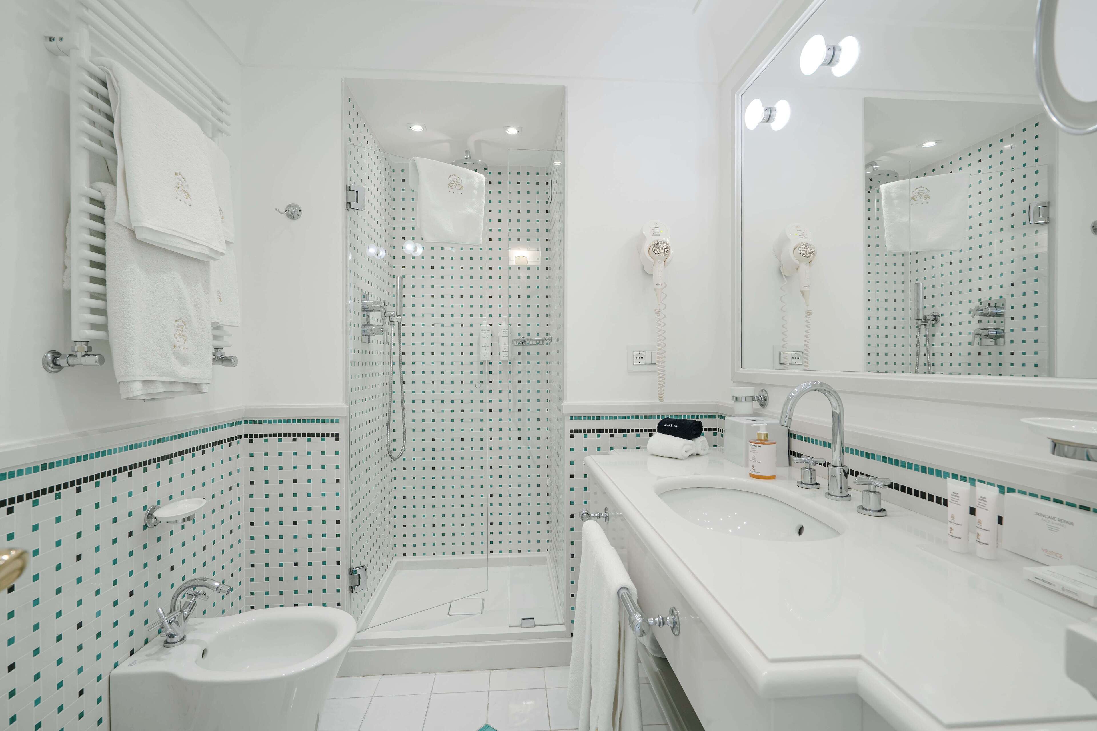 A modern bathroom with a glass-enclosed shower, a sink, and a large mirror.
