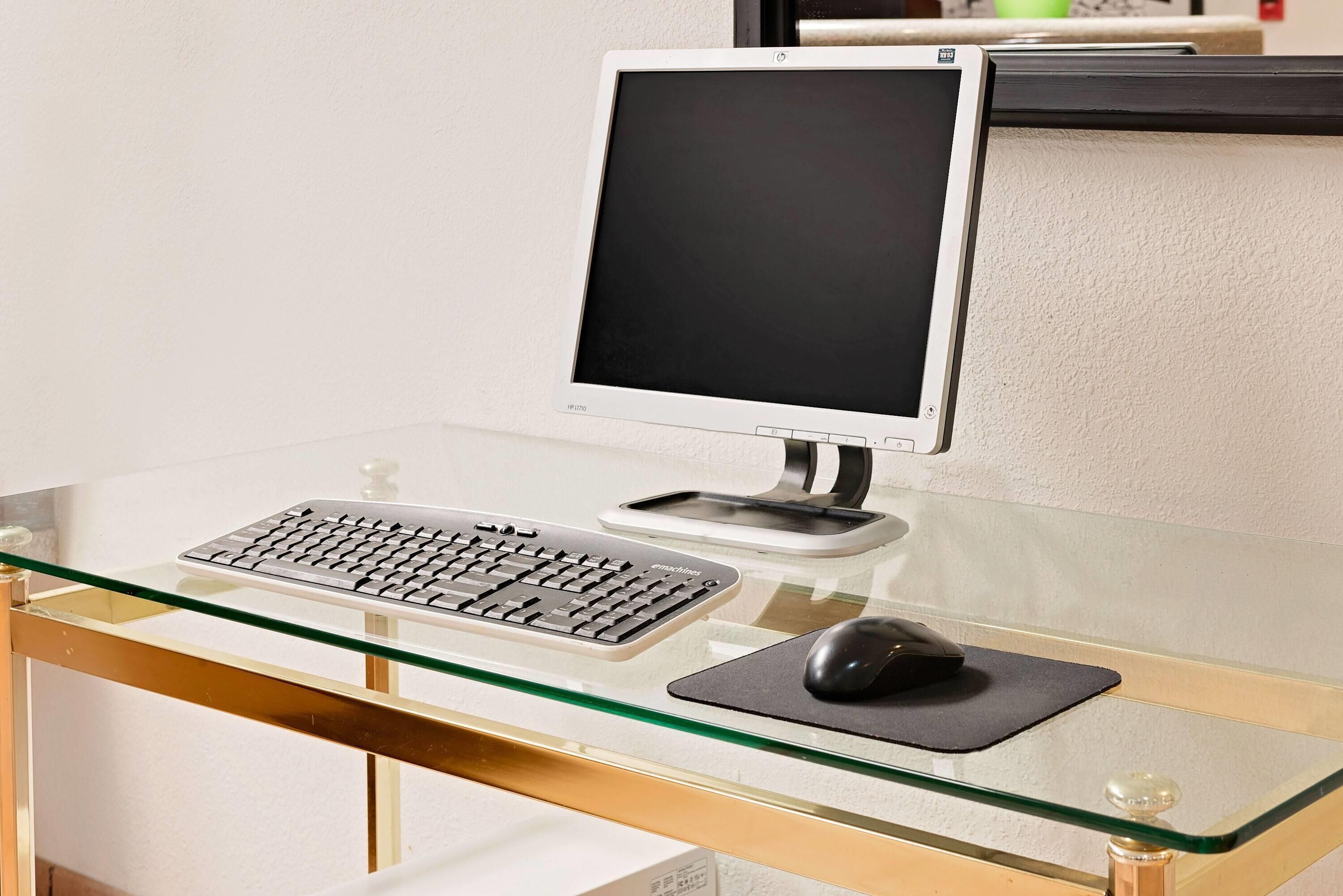 A computer desk with a monitor, keyboard, and mouse.