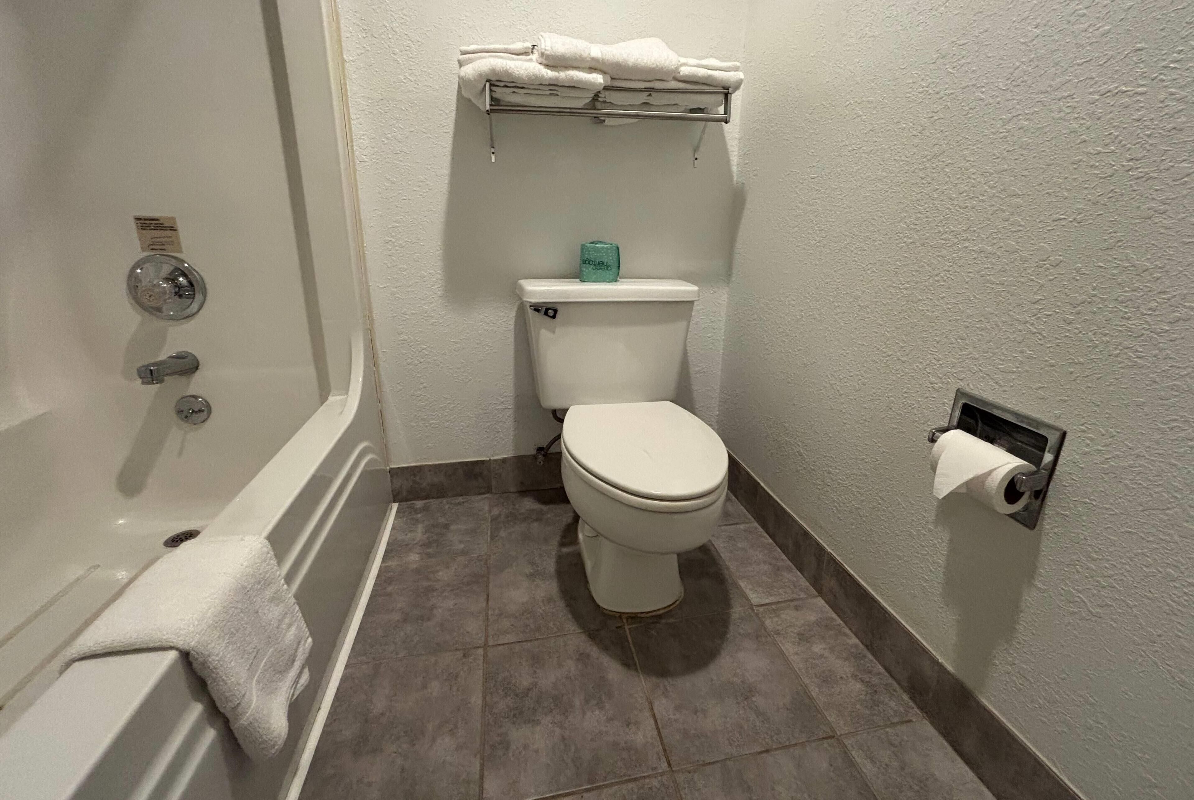A bathroom with a bathtub, toilet, and a towel rack.