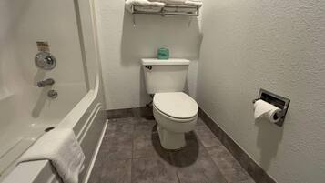 A bathroom with a bathtub, toilet, and a towel rack.