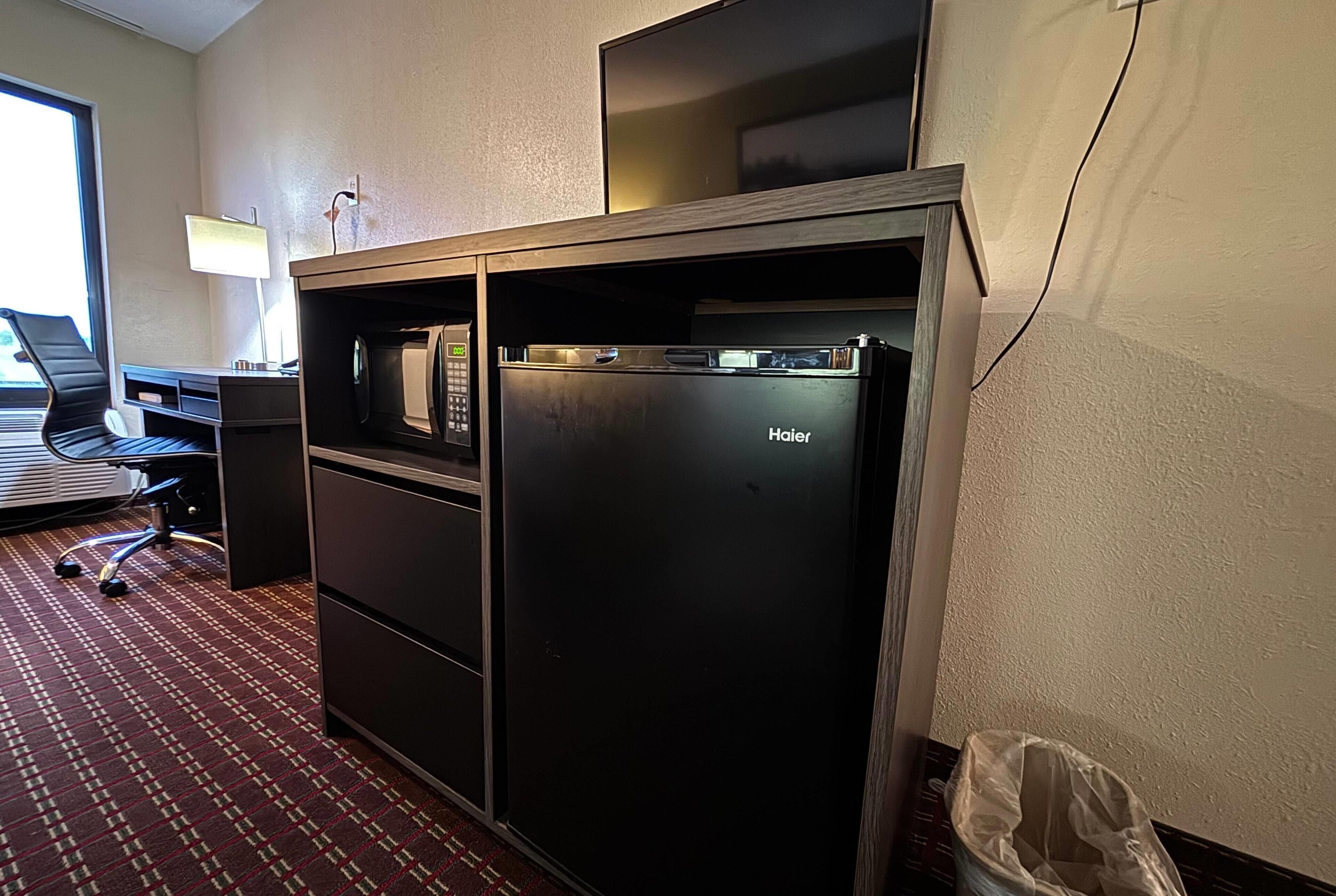Ein kompaktes Hotelzimmer mit Küchenzeile, einem Schreibtisch mit Laptop und einem Stuhl.