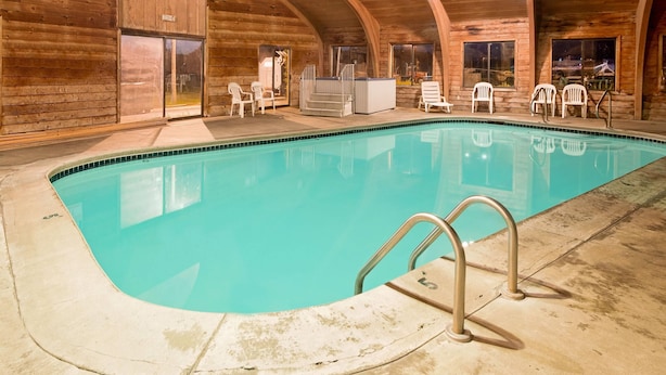 Una piscina interior con revestimiento de madera, un jacuzzi y varias sillas.