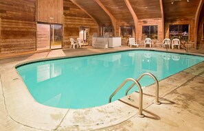 Une piscine intérieure avec un revêtement intérieur en bois, un jacuzzi et plusieurs chaises.
