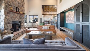A spacious living area with a stone fireplace, leather sofa, and a dining area with a high ceiling and wooden beams. - MTN Lodge Ridgway (Ridgway)