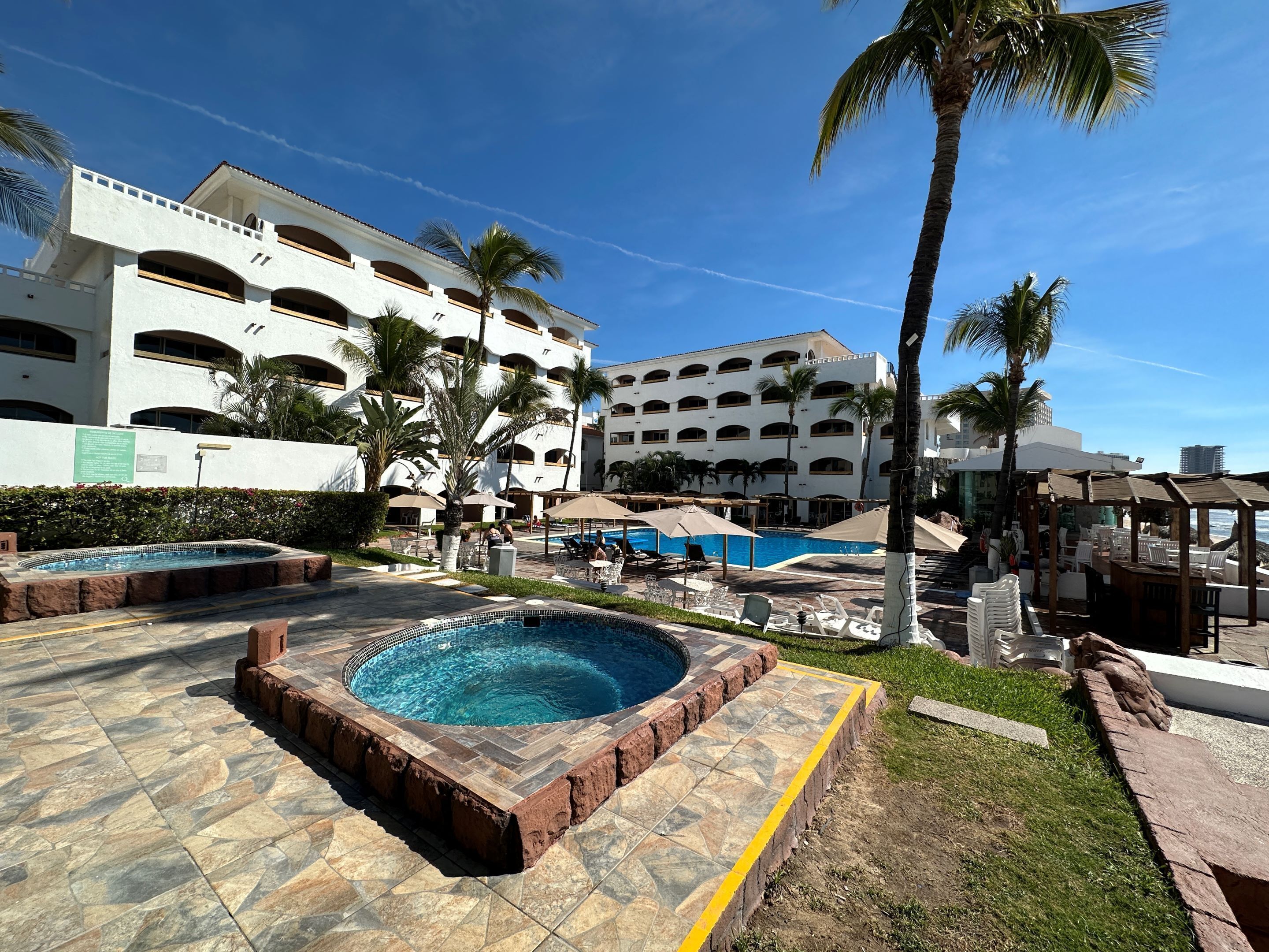 A resort pool area with multiple pools, palm trees, and a large building with multiple balconies.
