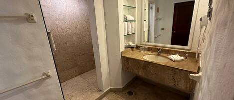 A bathroom with a marble sink, a large mirror, and a shower area.