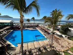 A pool area with lounge chairs and umbrellas, overlooking the ocean.