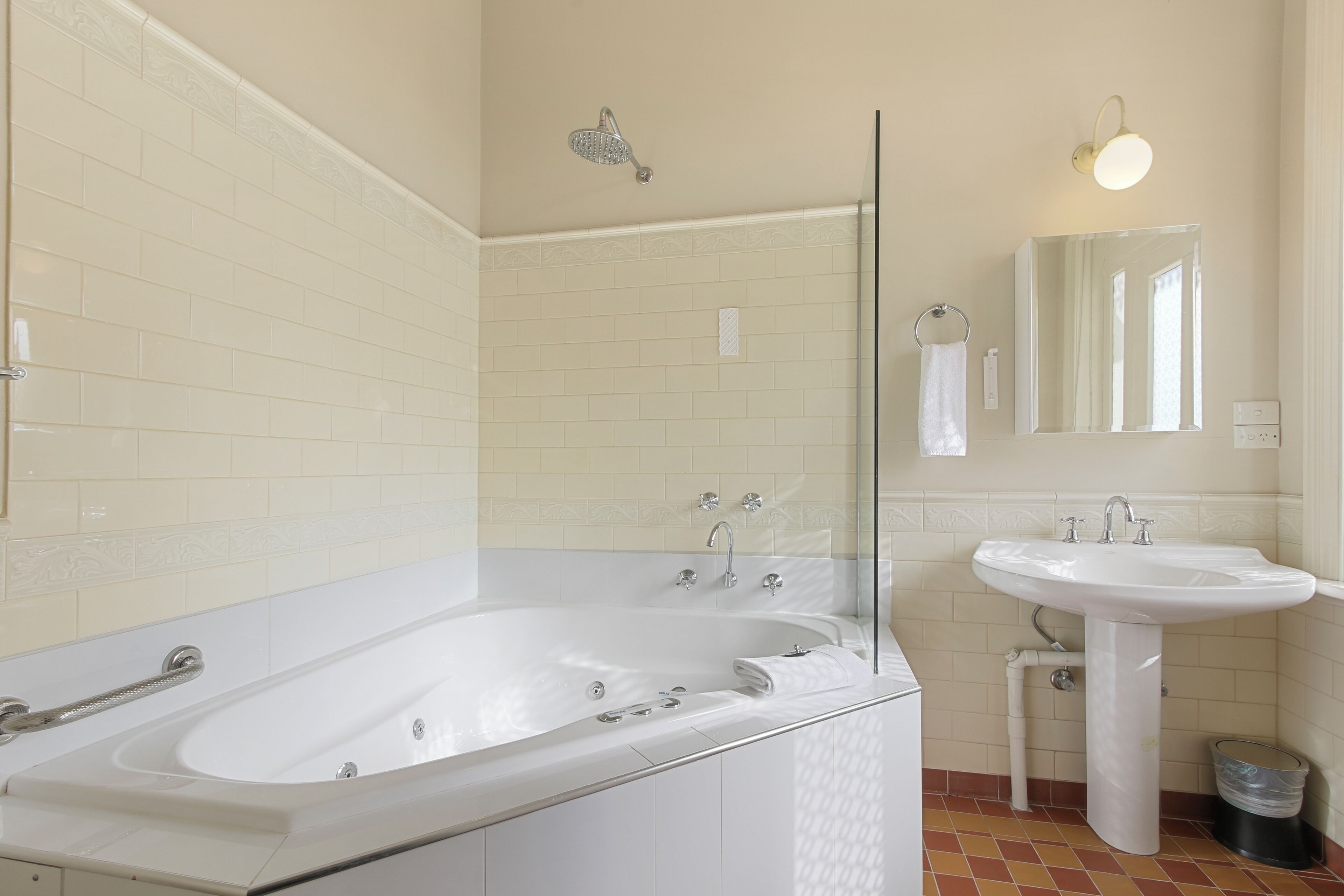 Une salle de bain moderne avec une grande baignoire, un lavabo sur colonne et un miroir.