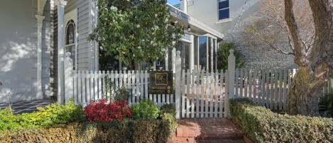 A white building with a reception sign, a white picket fence, and a brick pathway leading to the entrance.