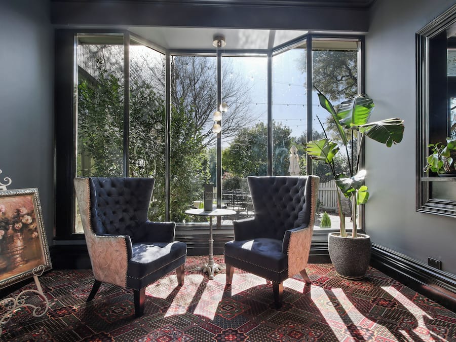 Une pièce comprenant deux fauteuils rembourrés, un tapis à motifs, un tableau encadré et une plante en pot.