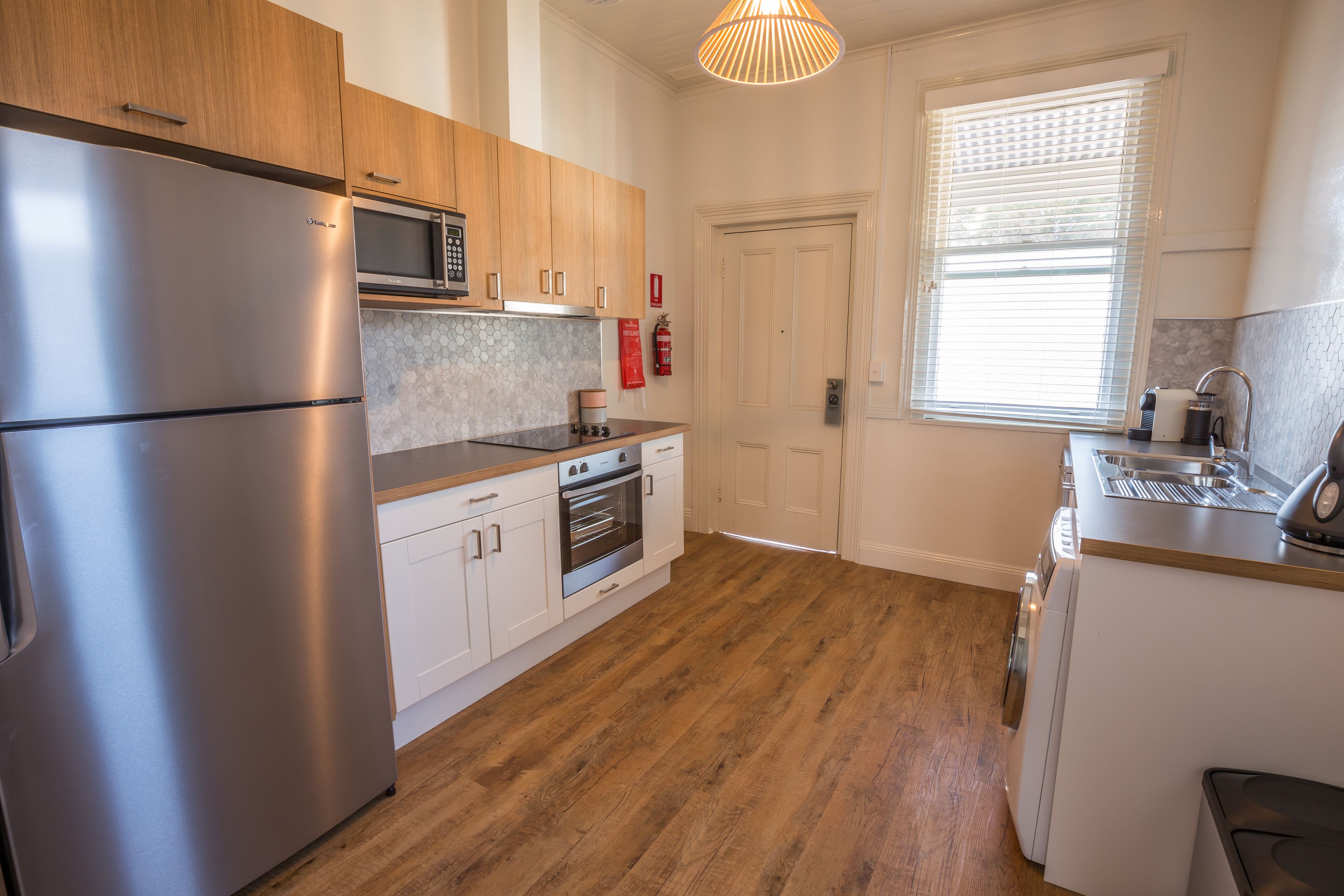 A modern kitchen with stainless steel appliances, wooden cabinets, and a tiled backsplash.