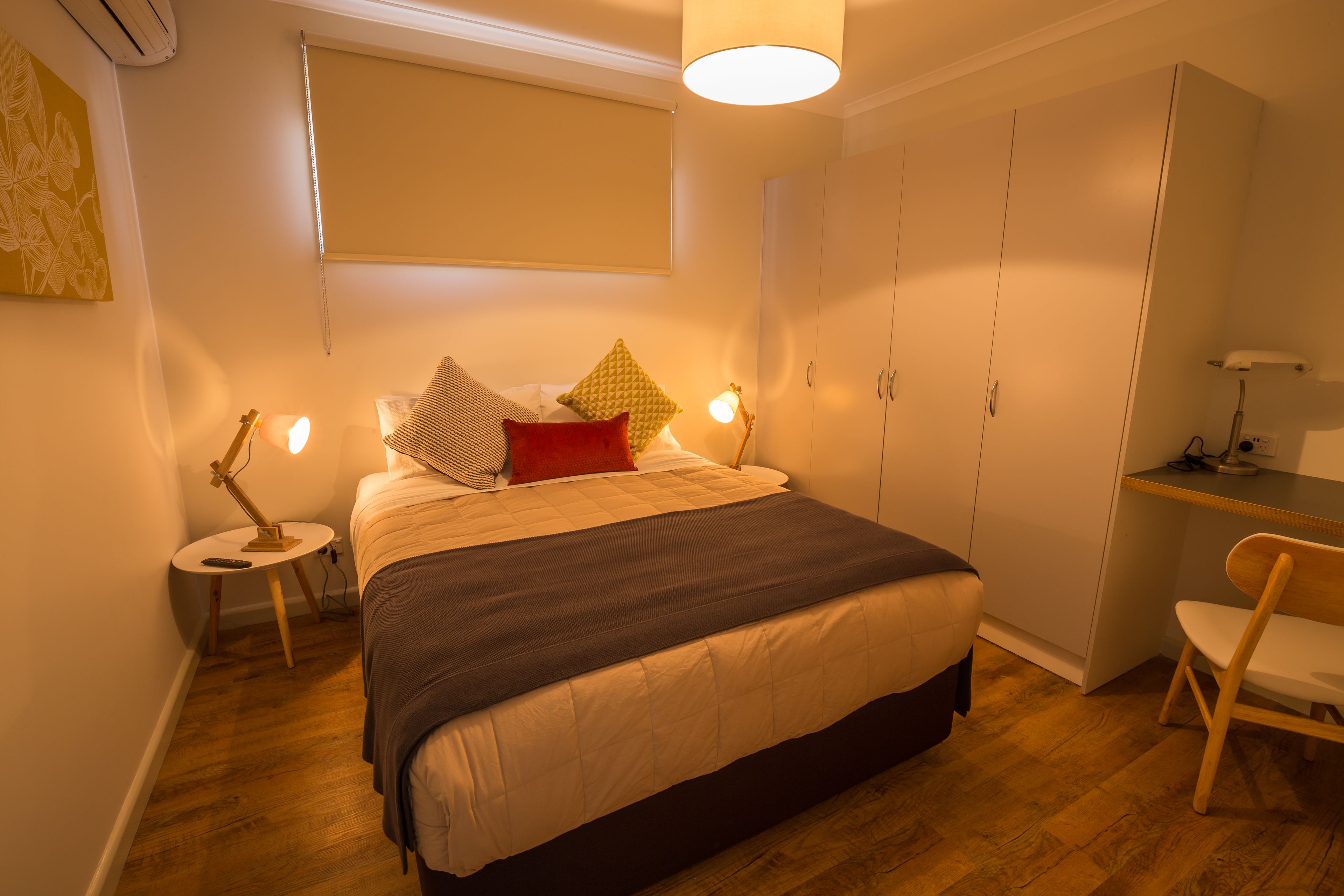 Une chambre à coucher comprenant un lit, des tables de chevet, une armoire et un bureau.