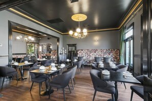 A restaurant with dark wood flooring, black chairs, and tables set for dining.