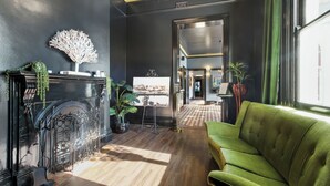 Habitación con chimenea, sofá verde y un ventanal amplio.