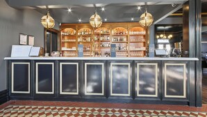 Zona de bar con mostrador, estantes llenos de botellas y luces colgantes.