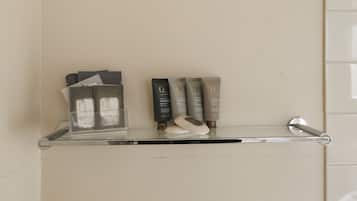 Un estante de baño con artículos de aseo, incluyendo un portalápices para cepillos de dientes, un dispensador de jabón y varias botellas de crema hidratante.