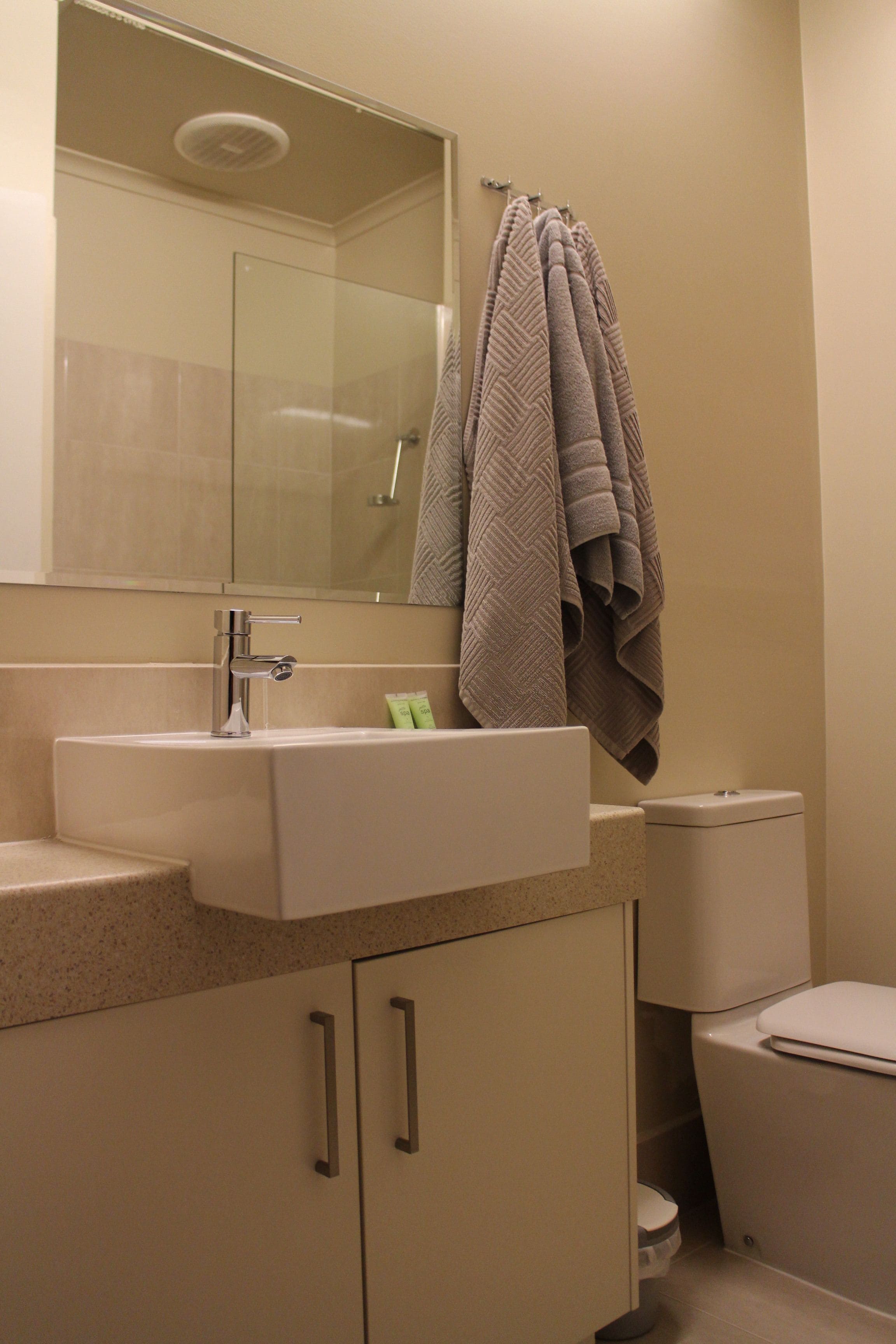A bathroom with a sink, mirror, and towel rack.