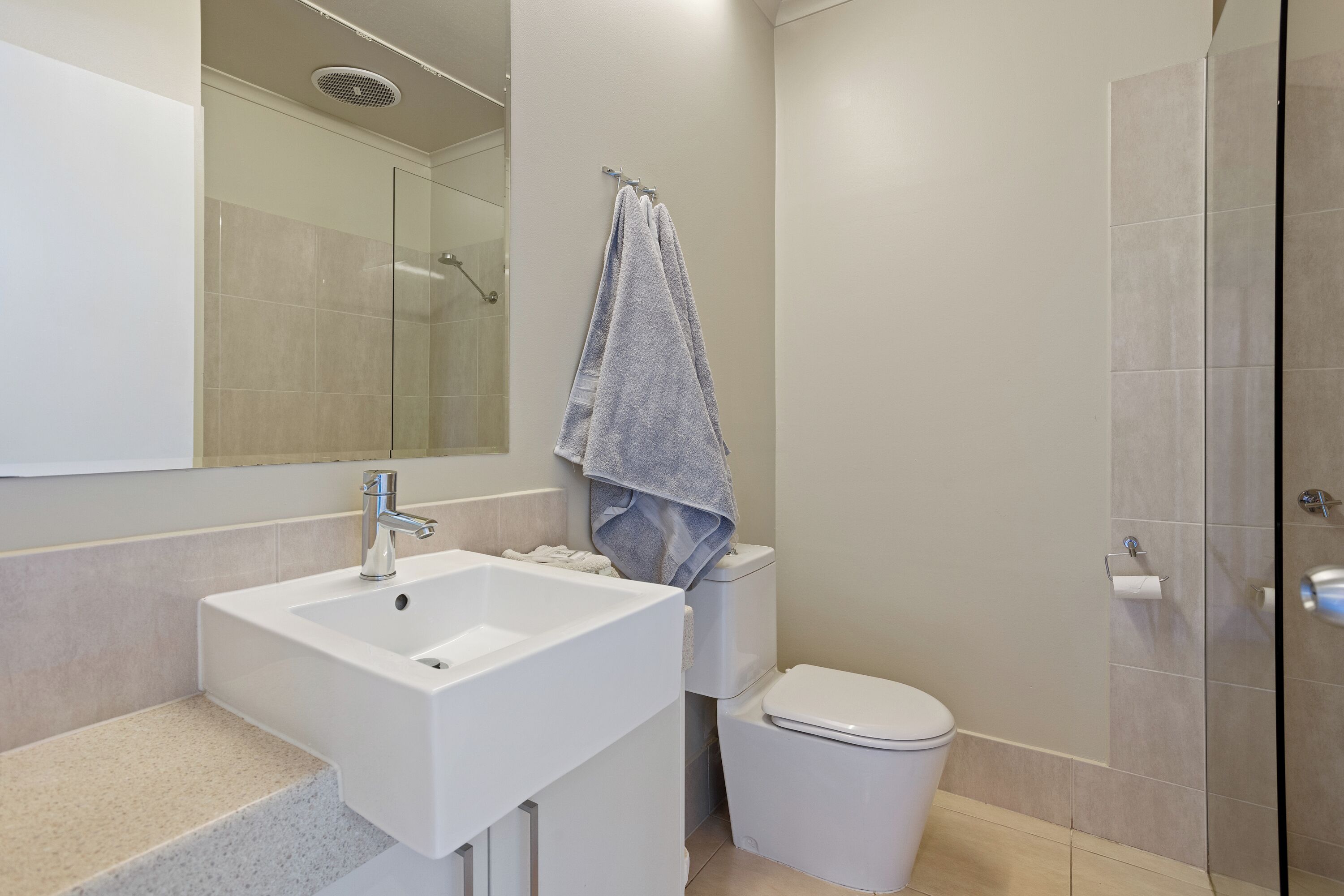 A bathroom with a white sink, a toilet, and a glass shower enclosure.