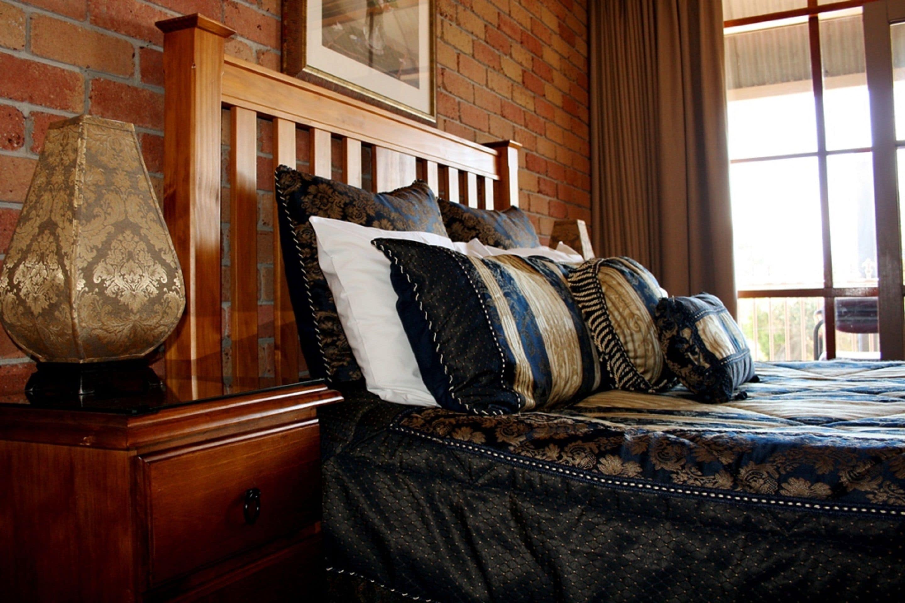 A bedroom with a wooden headboard, a large globe on a nightstand, and a patterned bedspread.