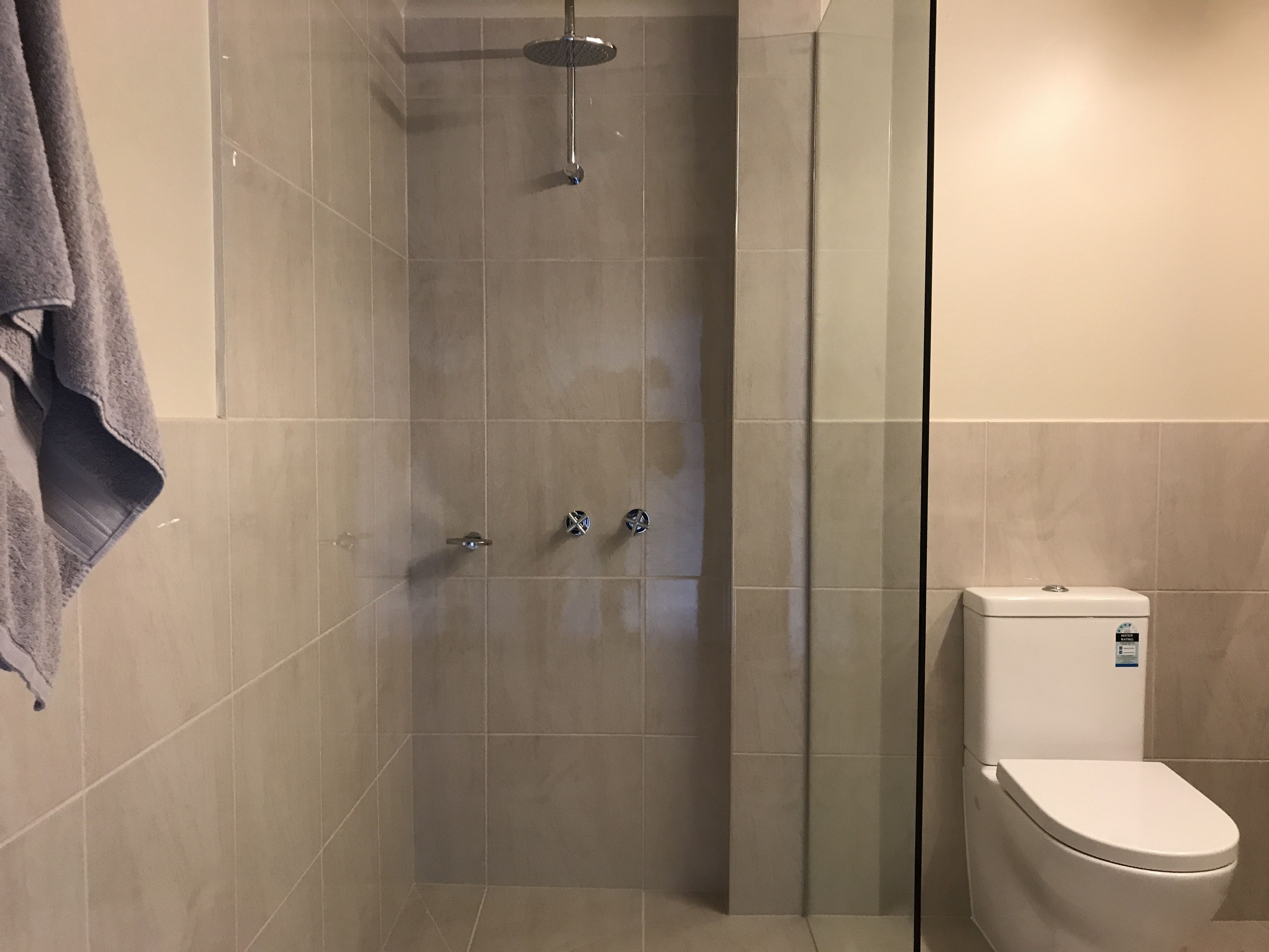 Ein modernes Badezimmer mit einer gläsernen Duschkabine, einer Toilette und einem Handtuch an der Wand.