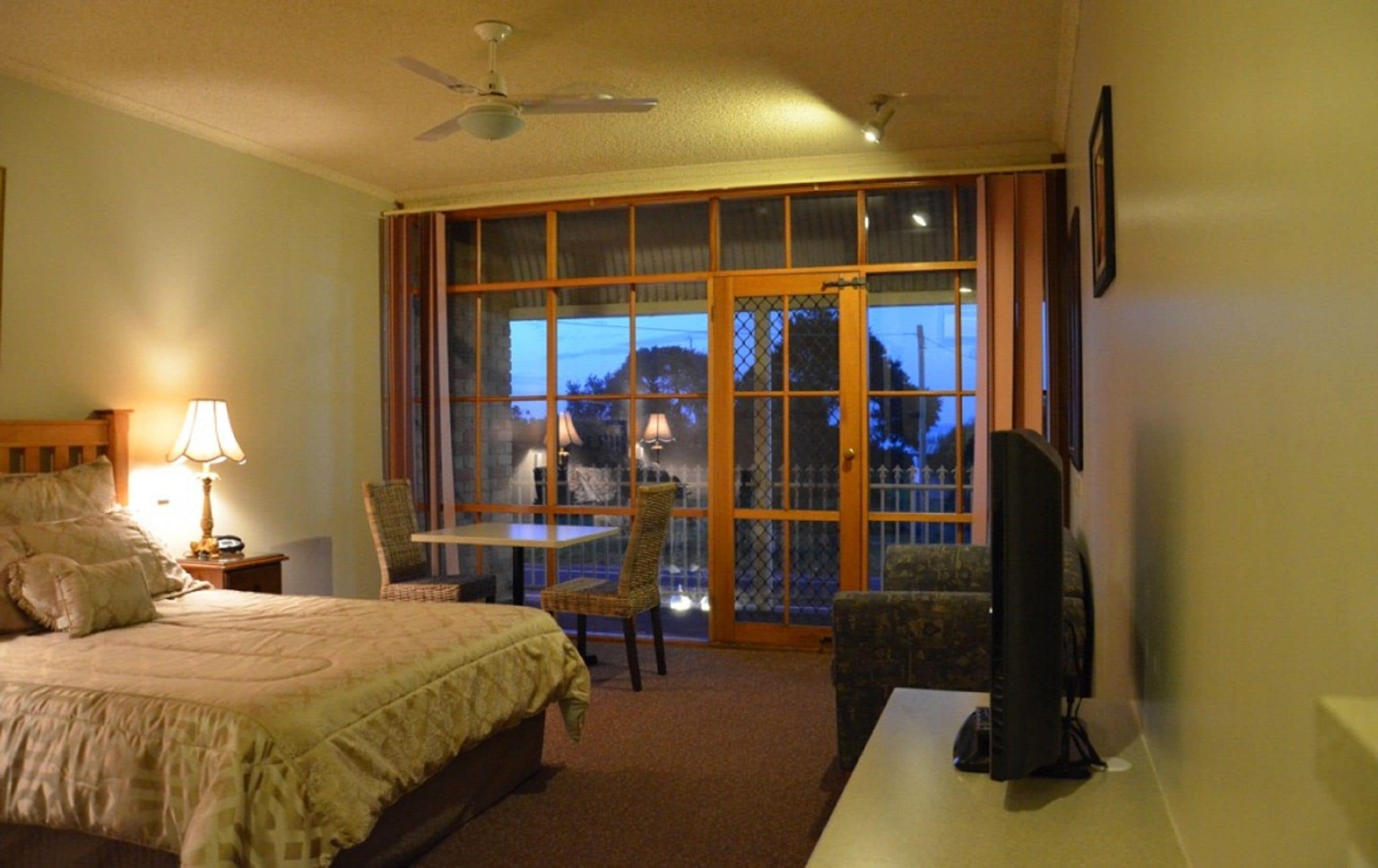 A hotel room with a bed, a desk, a chair, a TV, and a window with a view of a mountain.