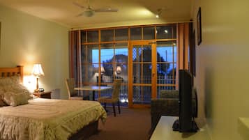 A hotel room with a bed, a desk, a chair, a TV, and a window with a view of a mountain.