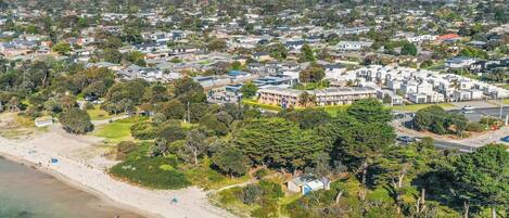 An aerial view of a coastal residential area with houses, a beach, and clear skies.