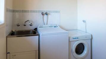 A laundry room with a washing machine, a dryer, and a sink.