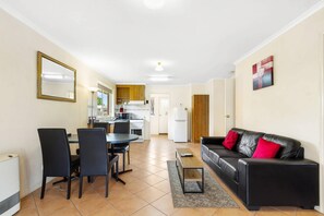A compact living space with a dining area, kitchen, and a sofa with red cushions. - Comfort Inn & Suites King Avenue (Sale)