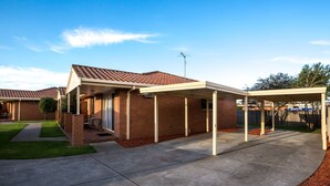 A residential house with a covered patio, brick exterior, and a well-maintained lawn. - Comfort Inn & Suites King Avenue (Sale)