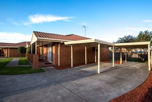 A residential house with a covered patio, brick exterior, and a well-maintained lawn. - Comfort Inn & Suites King Avenue (Sale)