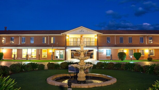 A hotel with a central fountain, a well-maintained lawn, and a brick facade. - Comfort Inn & Suites King Avenue (Sale)