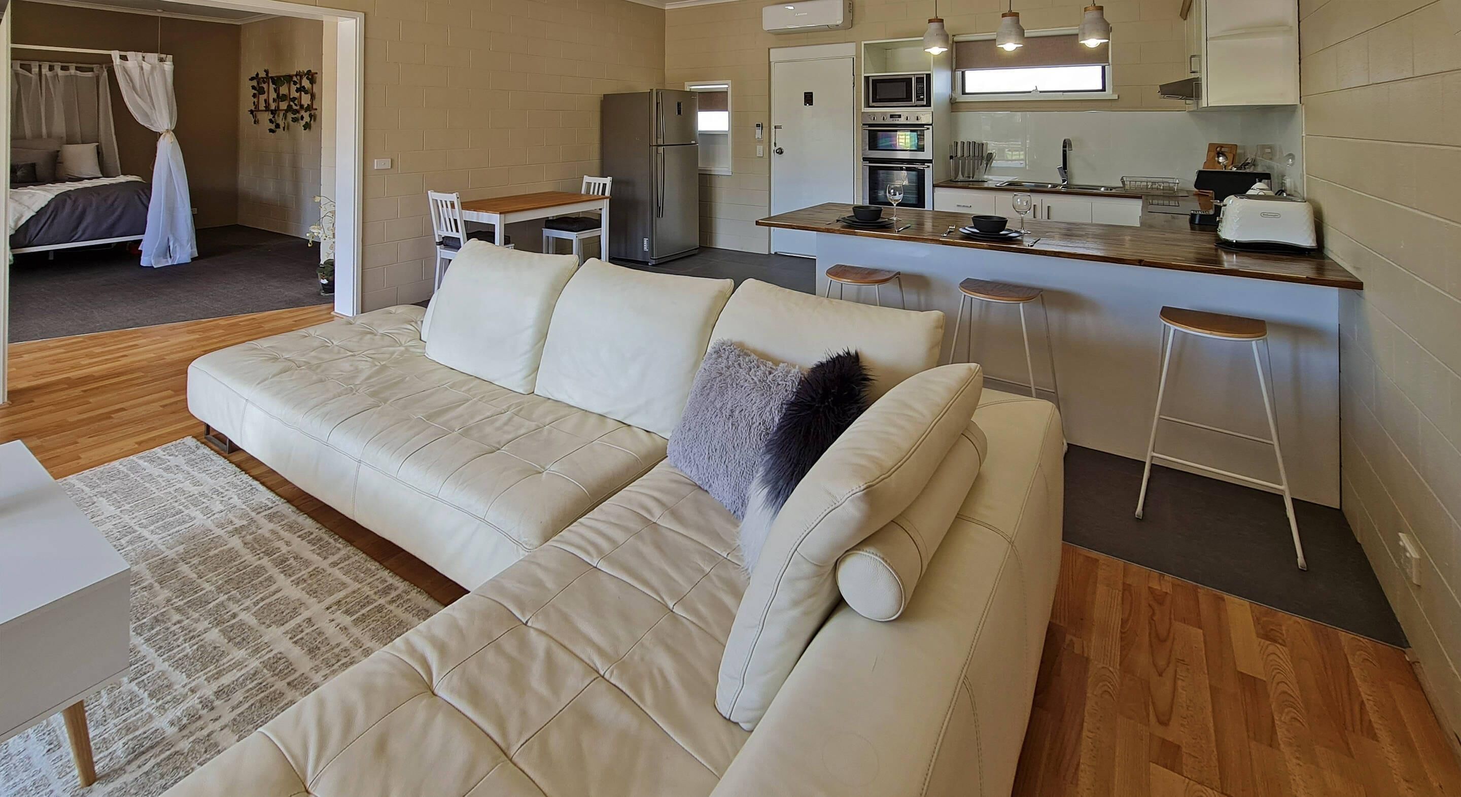 Ein modernes Wohnzimmer mit Sofa, Essbereich und einer Küchenzeile.