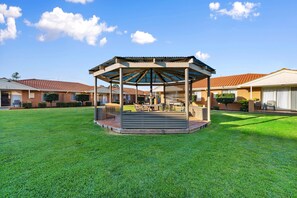 A gazebo with a roof and seating area in a grassy courtyard, surrounded by brick buildings with tiled roofs. - Comfort Inn & Suites King Avenue (Sale)