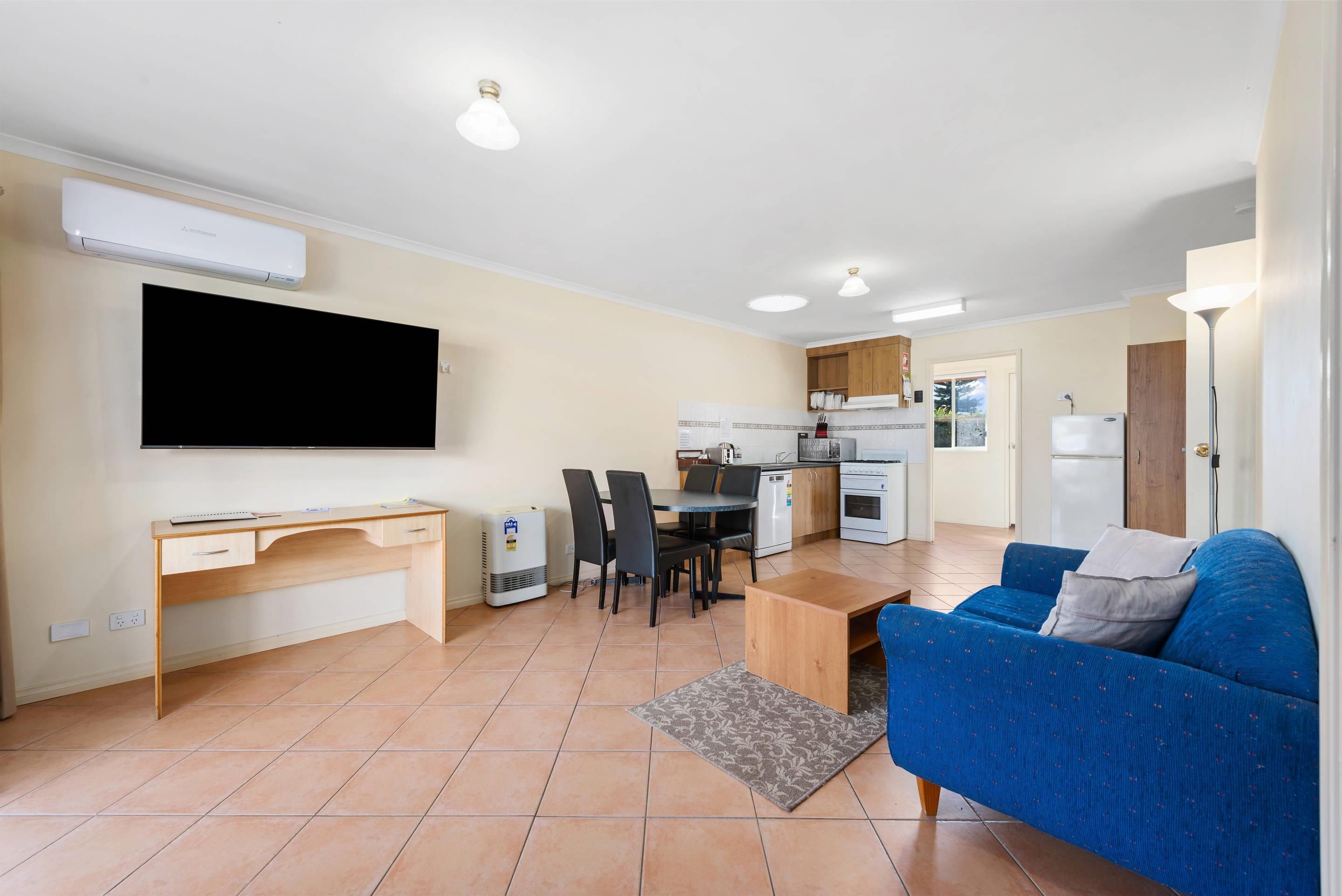 Un apartamento moderno con sala de estar, comedor, kitchenette y televisor montado en la pared.
