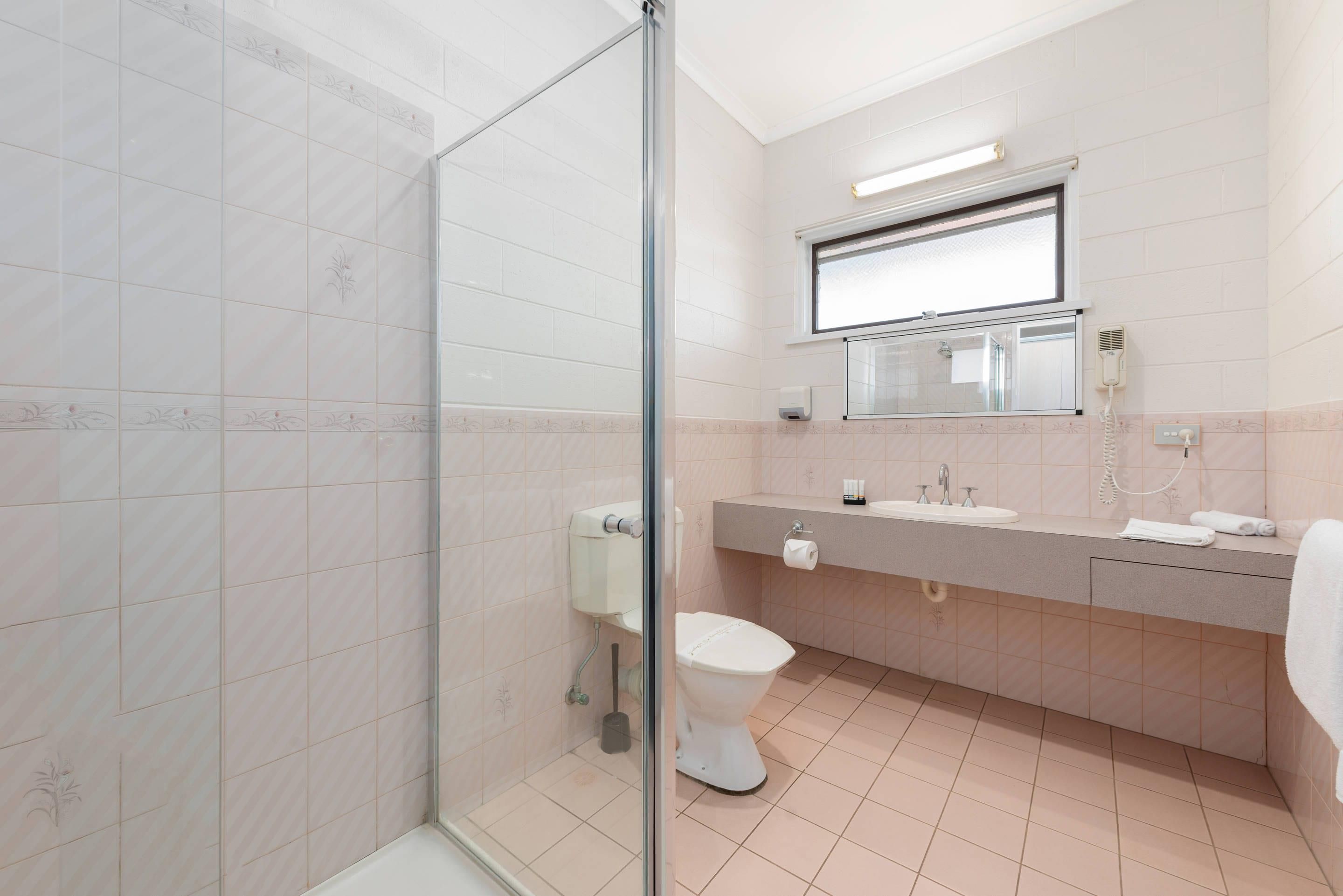 Casa de banho moderna com cabine de duche em vidro, sanita, lavatório com espelho e porta-toalhas.