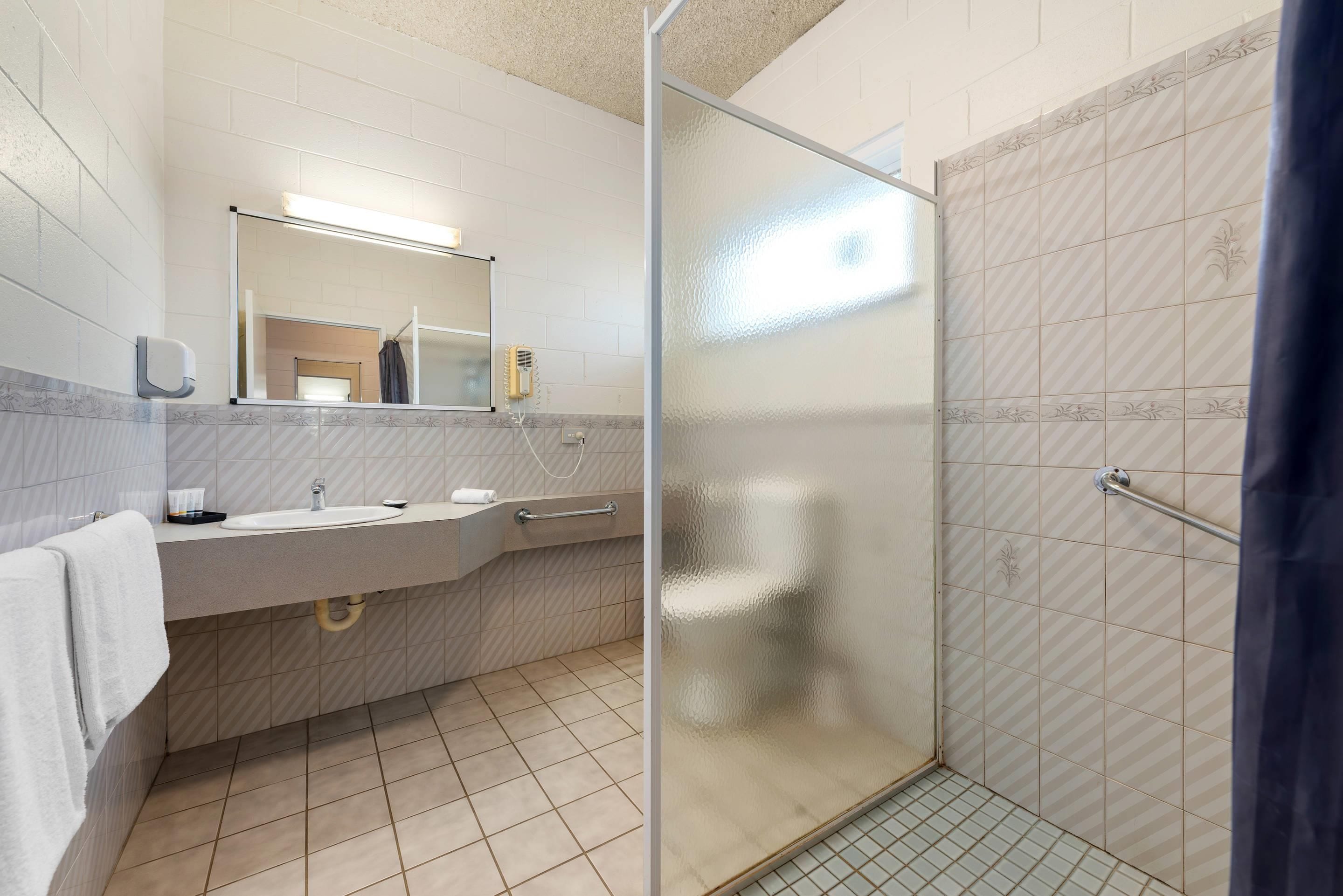 A bathroom with a shower, sink, and mirror.