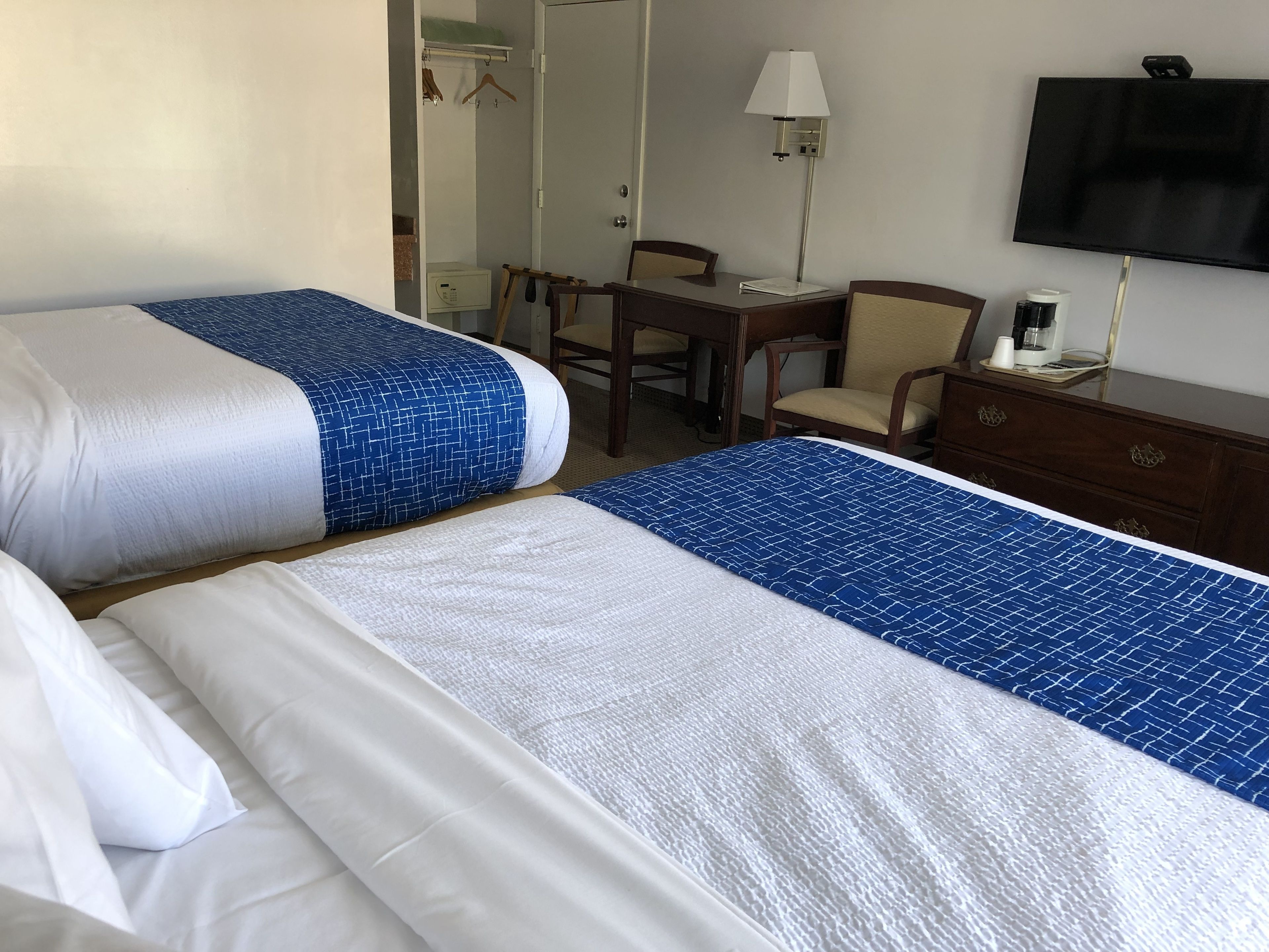Una habitación de hotel con dos camas, un escritorio, una silla, un televisor y un aparador.