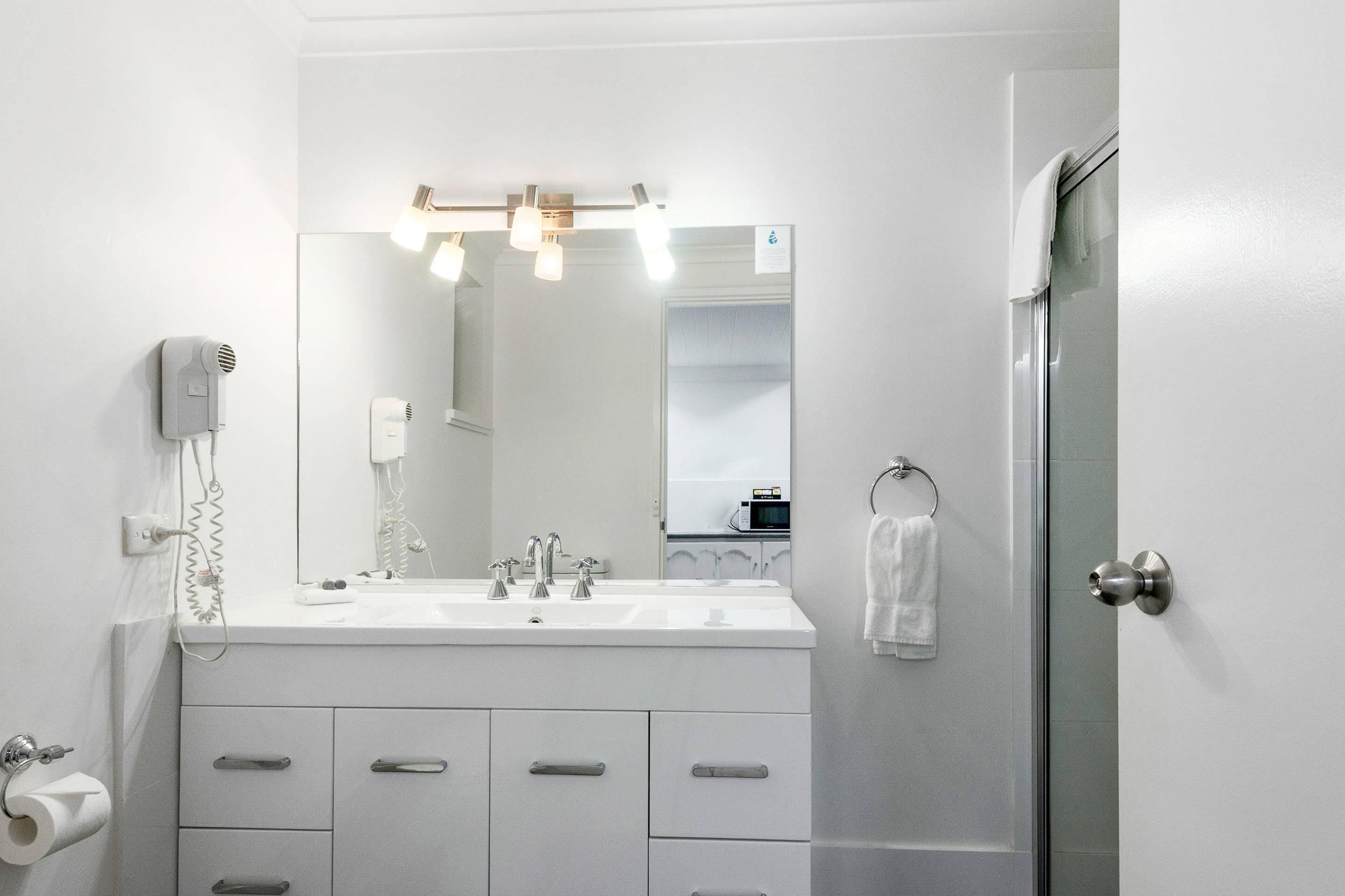 Un baño moderno con un espejo grande, dos lavamanos, un secador de pelo y un perchero para toallas.