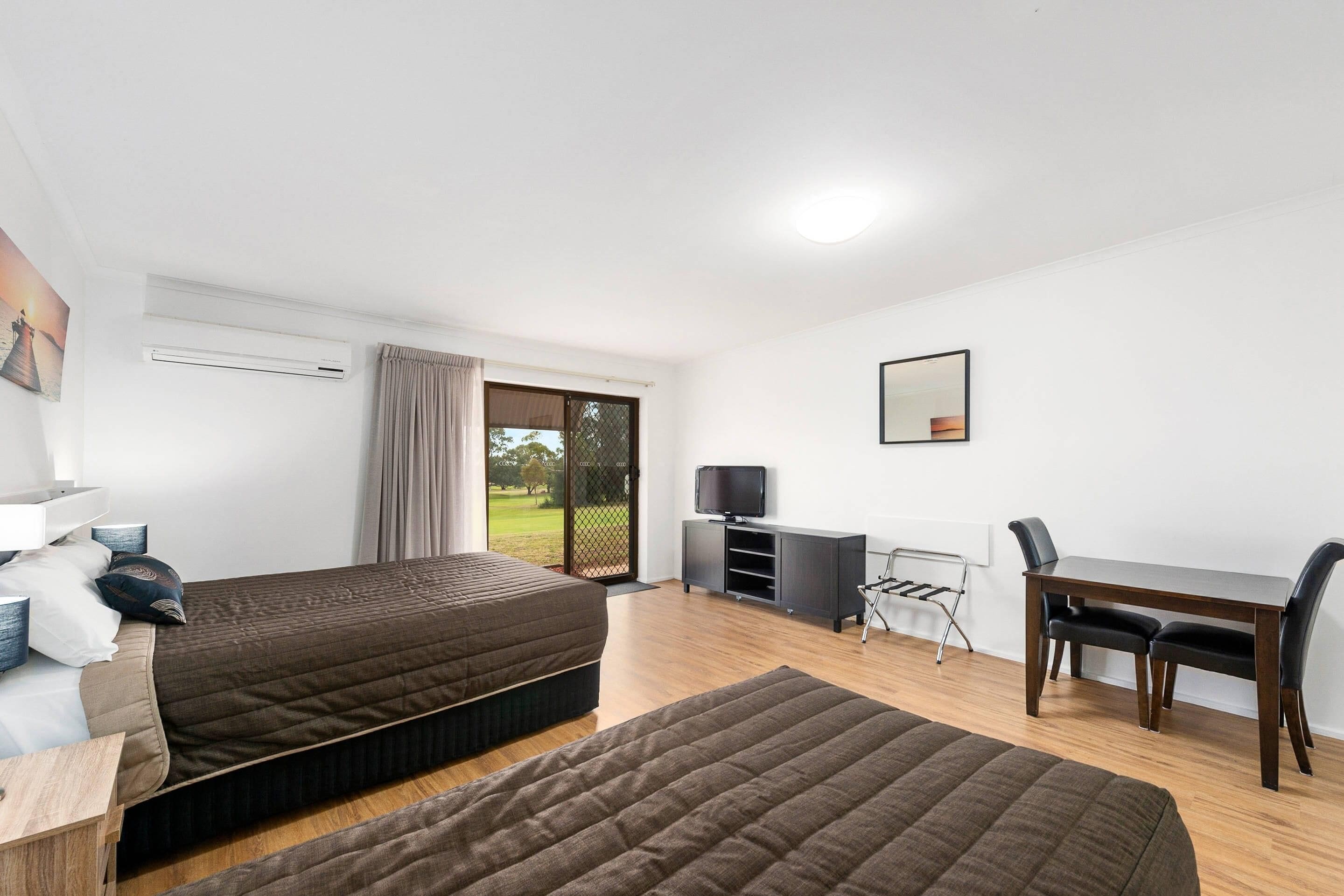 Habitación de hotel moderna con dos camas, un escritorio, un televisor y vistas al exterior.