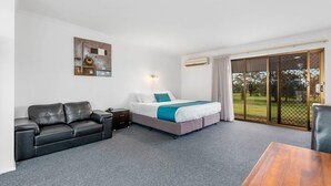 A hotel room with a bed, a sofa, a table, and a painting on the wall. - Comfort Inn & Suites Riverland (Barmera)