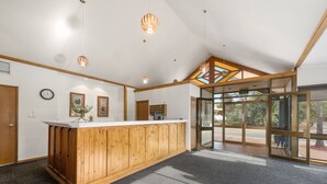 A reception area with a wooden counter, a clock, framed pictures, and a large glass door leading outside. - Comfort Inn & Suites Riverland (Barmera)