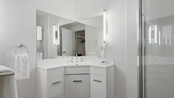 A modern bathroom with a white vanity, a large mirror, and a glass shower enclosure.